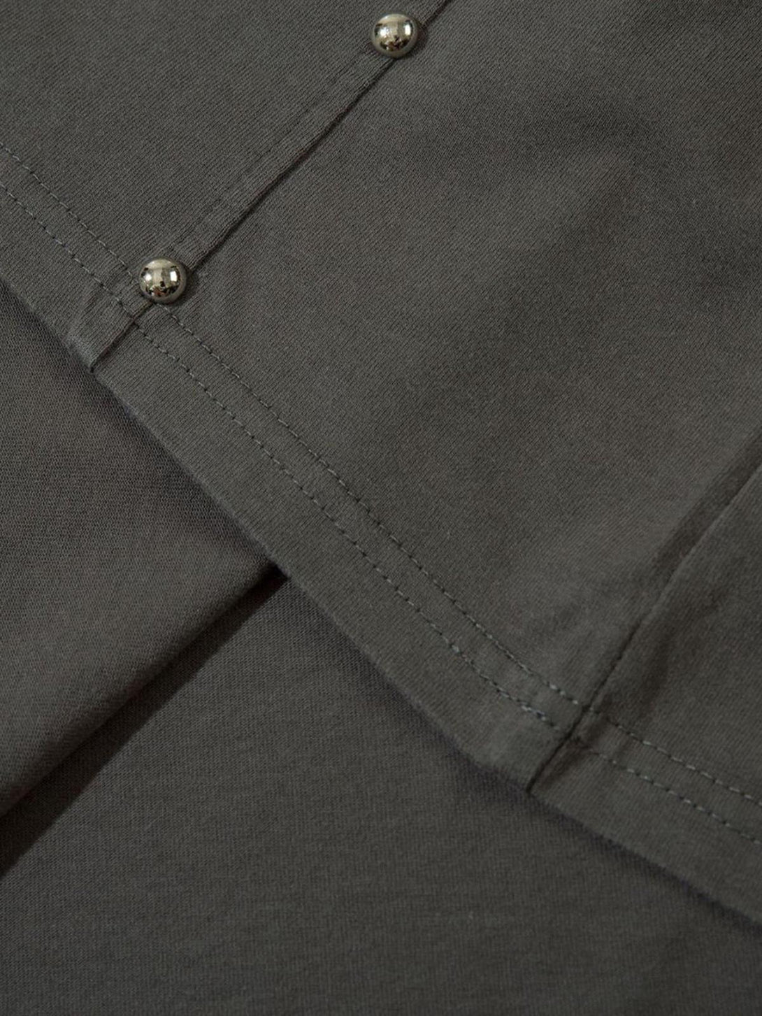 Detailed fabric and stitching with rivet accents on a gray T-shirt by TALISHKO.