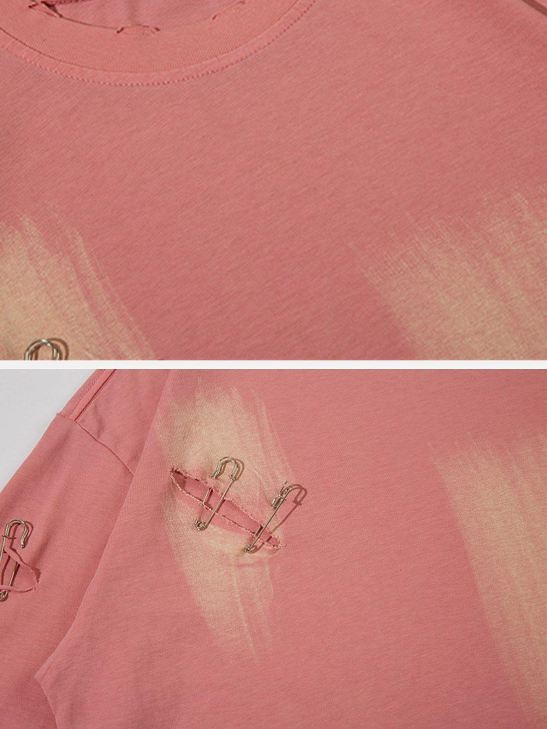 A detailed view of the pink tee's distressed fabric and safety pin accents by TALISHKO.