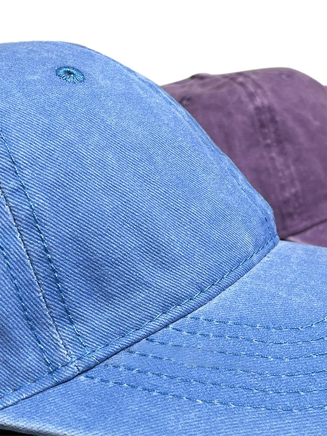 A close-up of blue and purple washed canvas caps by TALISHKO, highlighting texture and stitching.