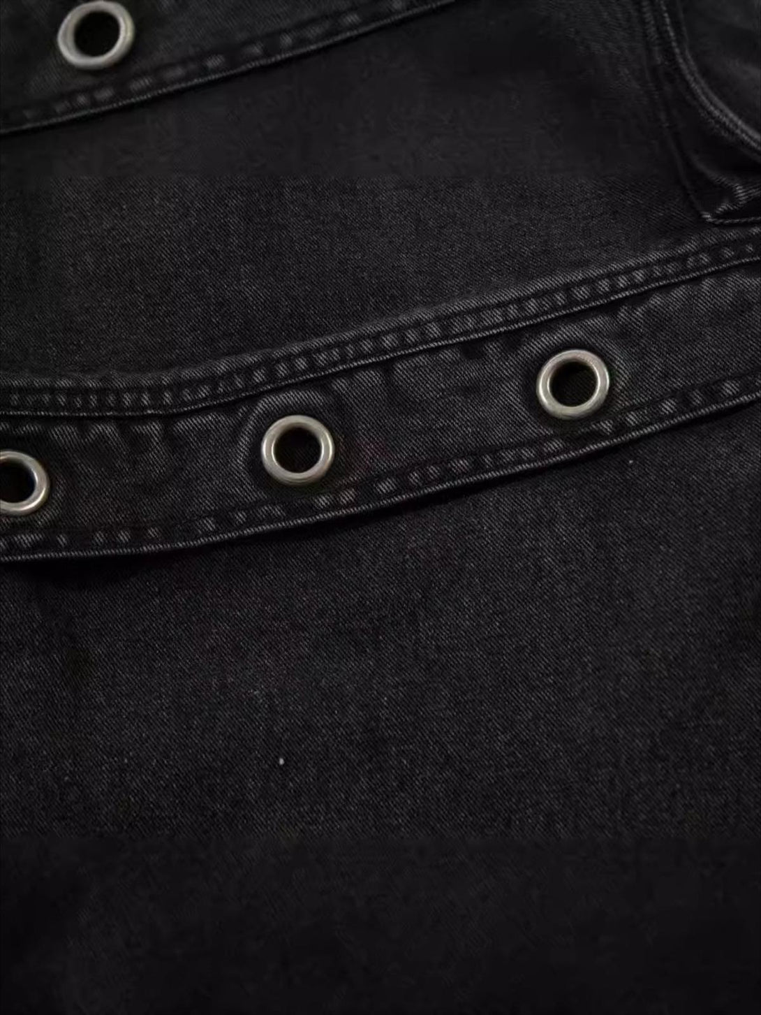 Detailed view of TALISHKO's washed cargo jeans, showcasing grommet detail and texture.