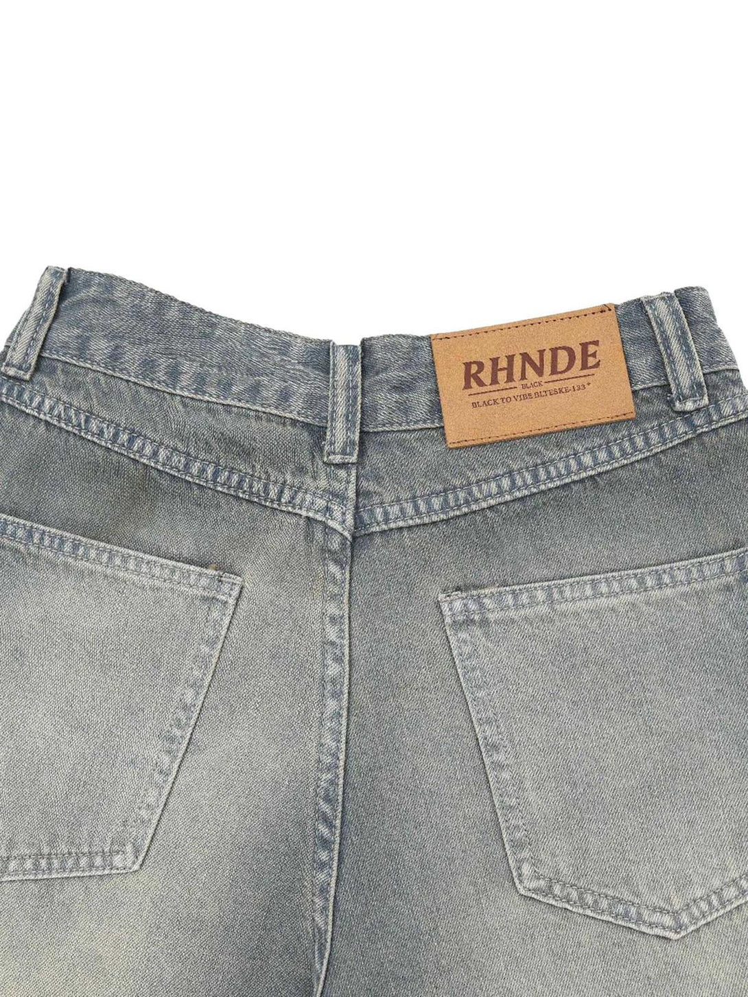 Back detail of washed denim hip-hop shorts by TALISHKO, highlighting the brand patch.