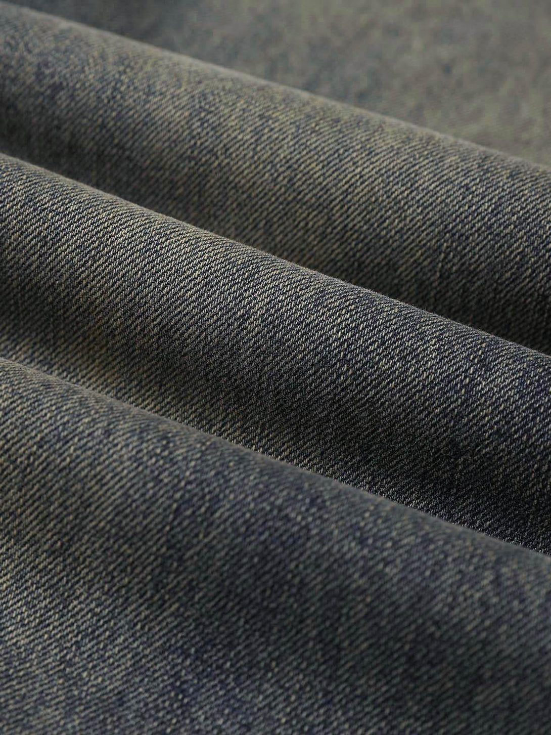 A tight crop highlighting TALISHKO's denim texture and pattern in washed dirty-dye straight jeans.