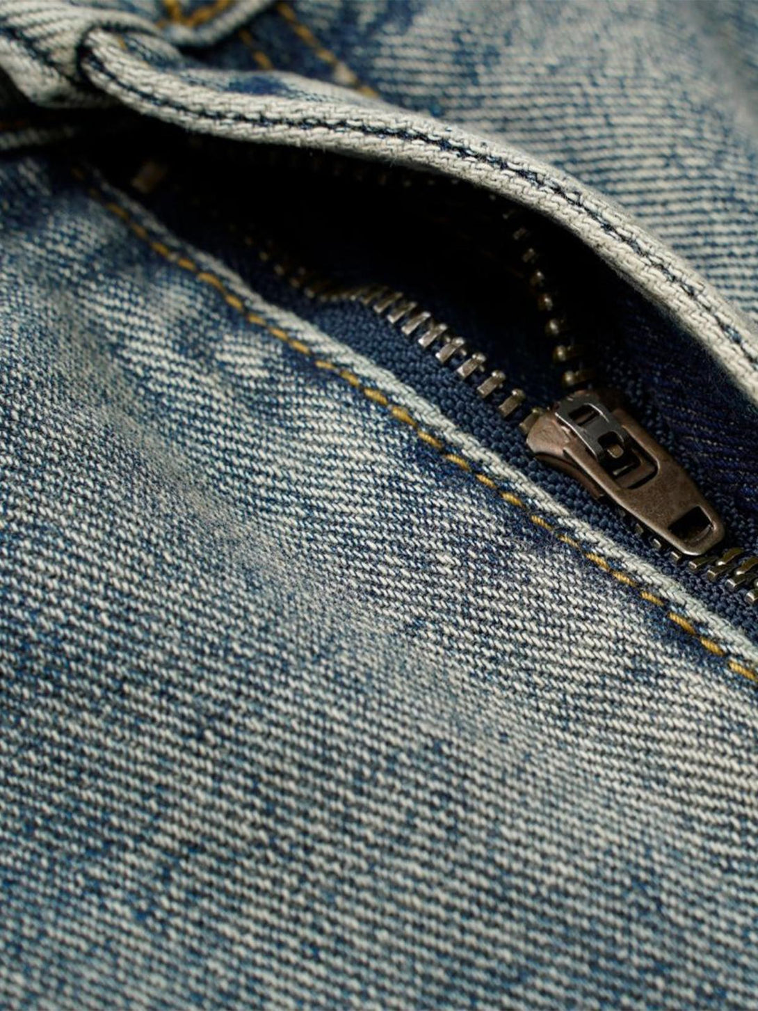 Detailed view of TALISHKO's deconstructed jeans, highlighting the zipper and distressed texture.