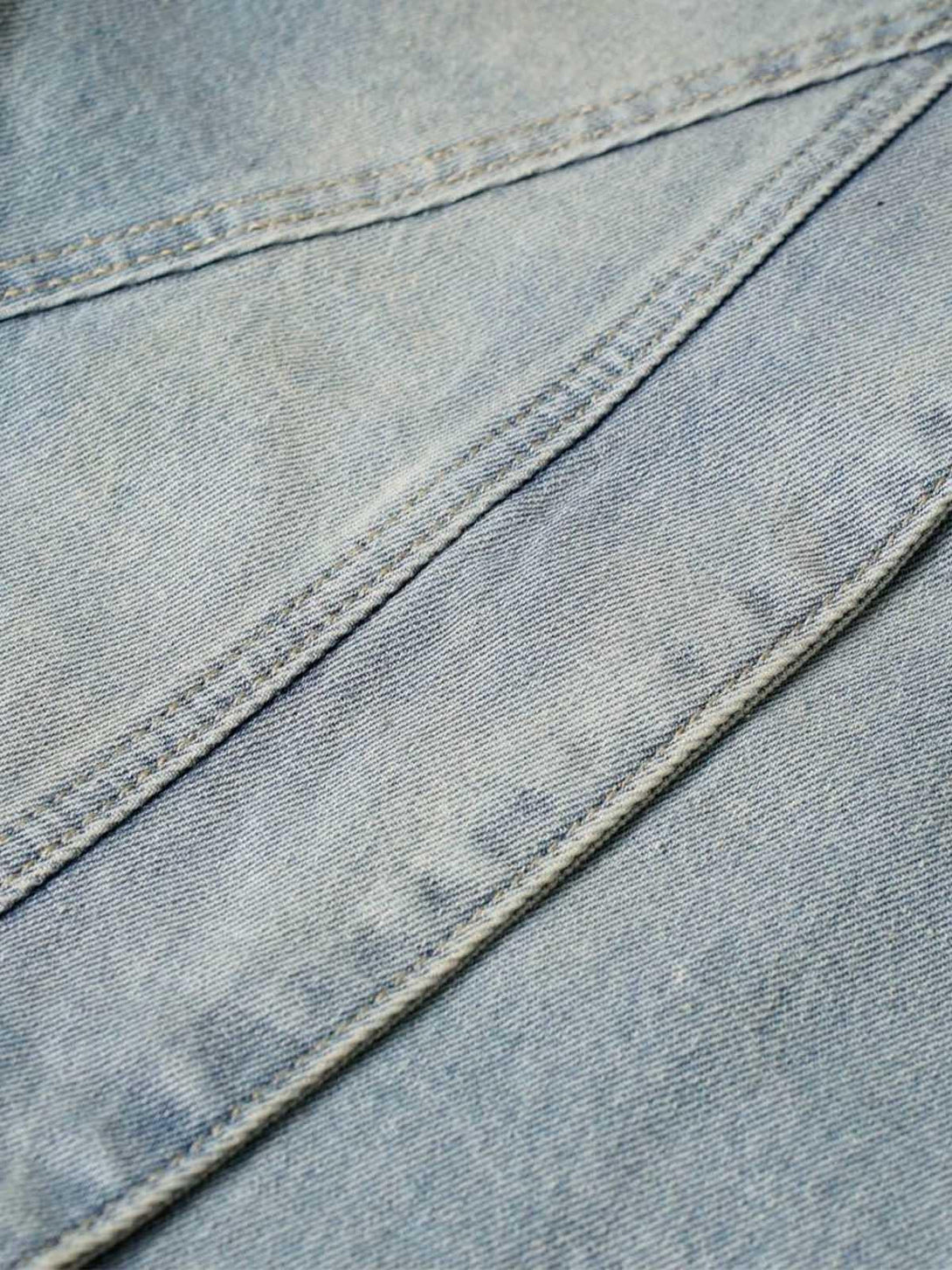 Intricate look at TALISHKO's washed distressed denim fabric, highlighting unique stitching.