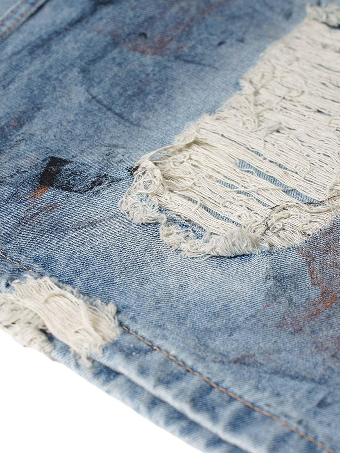 Zoomed-in texture of TALISHKO denim shorts showcasing distressed and ripped detailing.