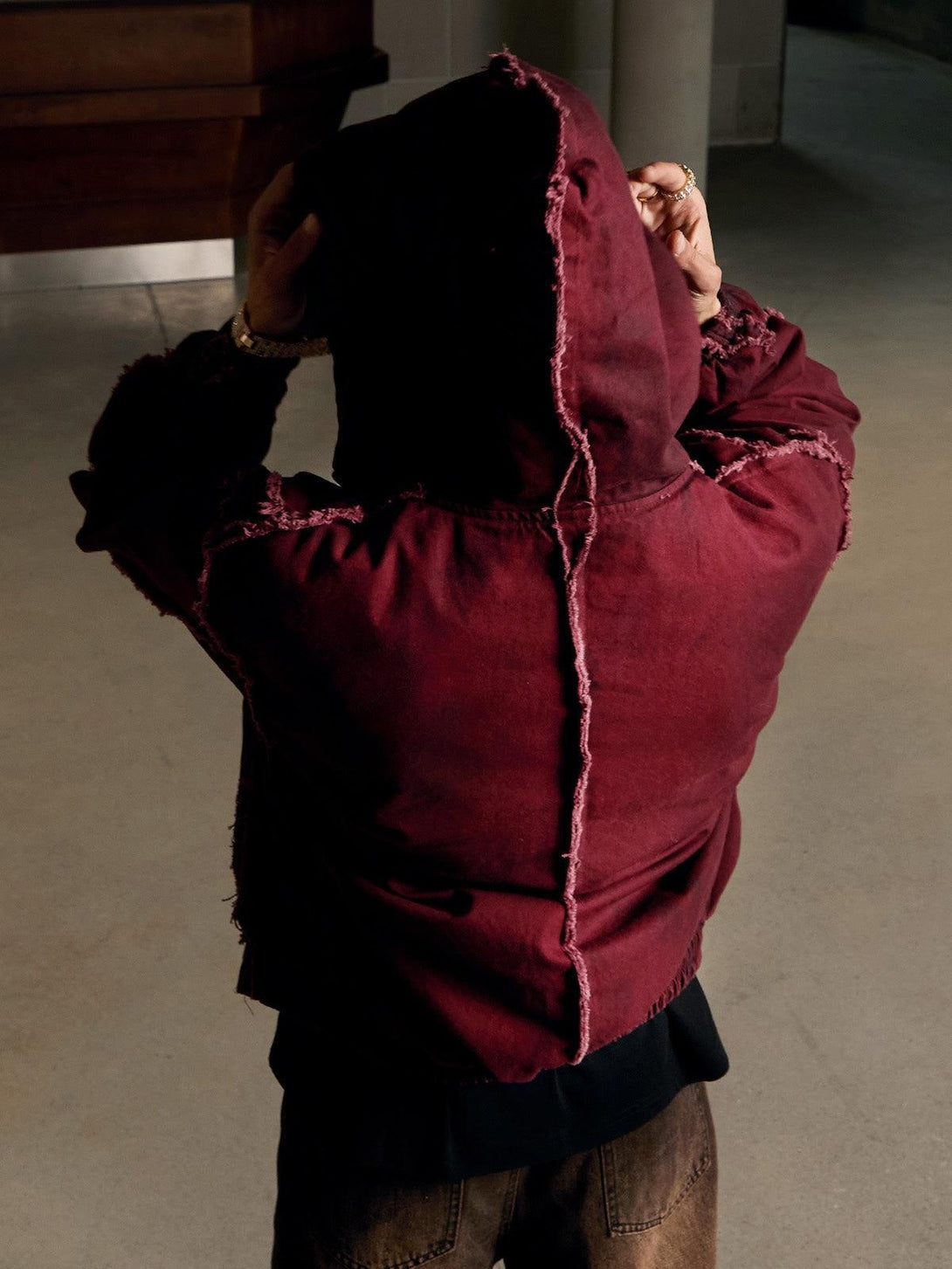Back view of a red washed distressed hooded jacket by TALISHKO, emphasizing its unique texture.