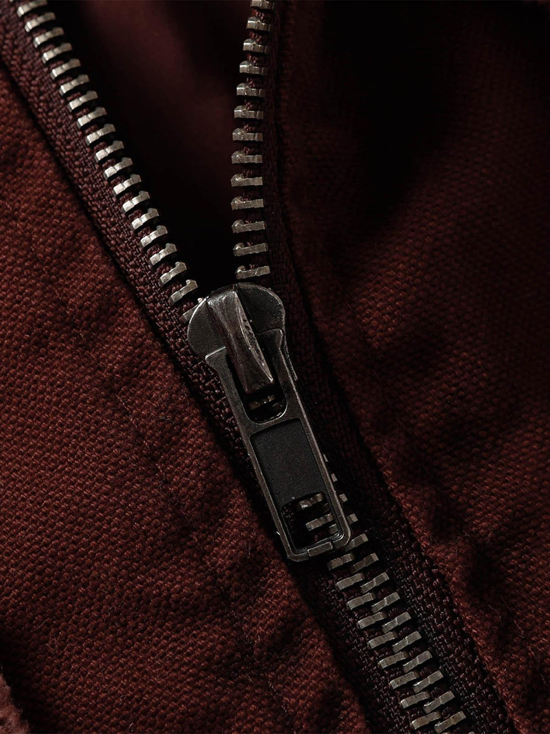 A close-up of the zipper on a washed distressed jacket by TALISHKO, highlighting rugged detail.