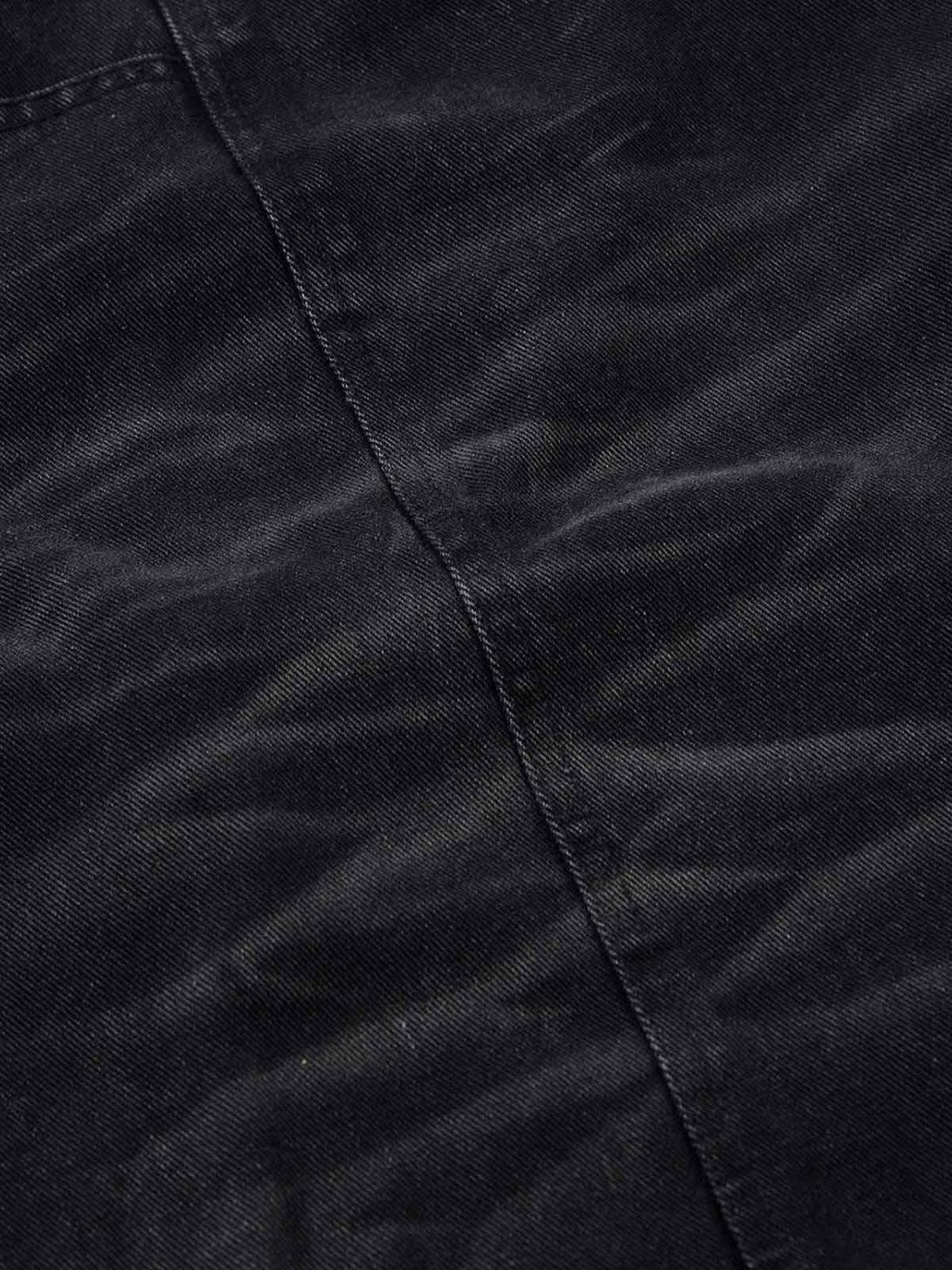 Zoomed-in texture of TALISHKO's black washed distressed cargo jeans, highlighting detailed stitching.