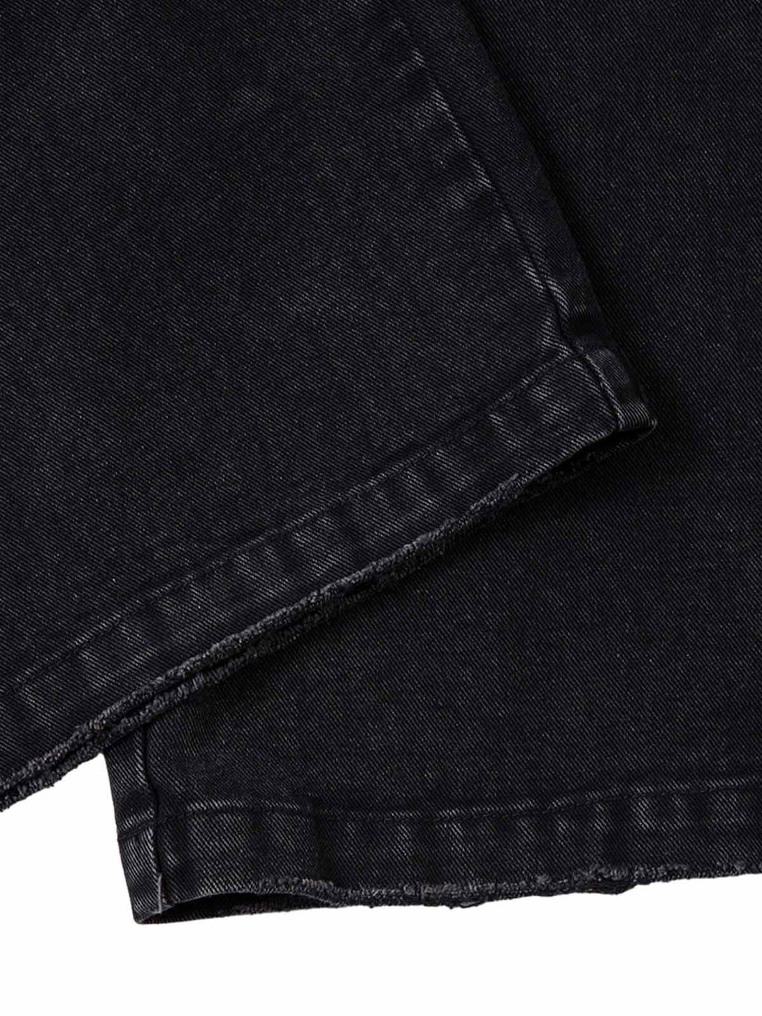 A detailed view of TALISHKO's black washed distressed cargo jeans hem, showcasing texture.