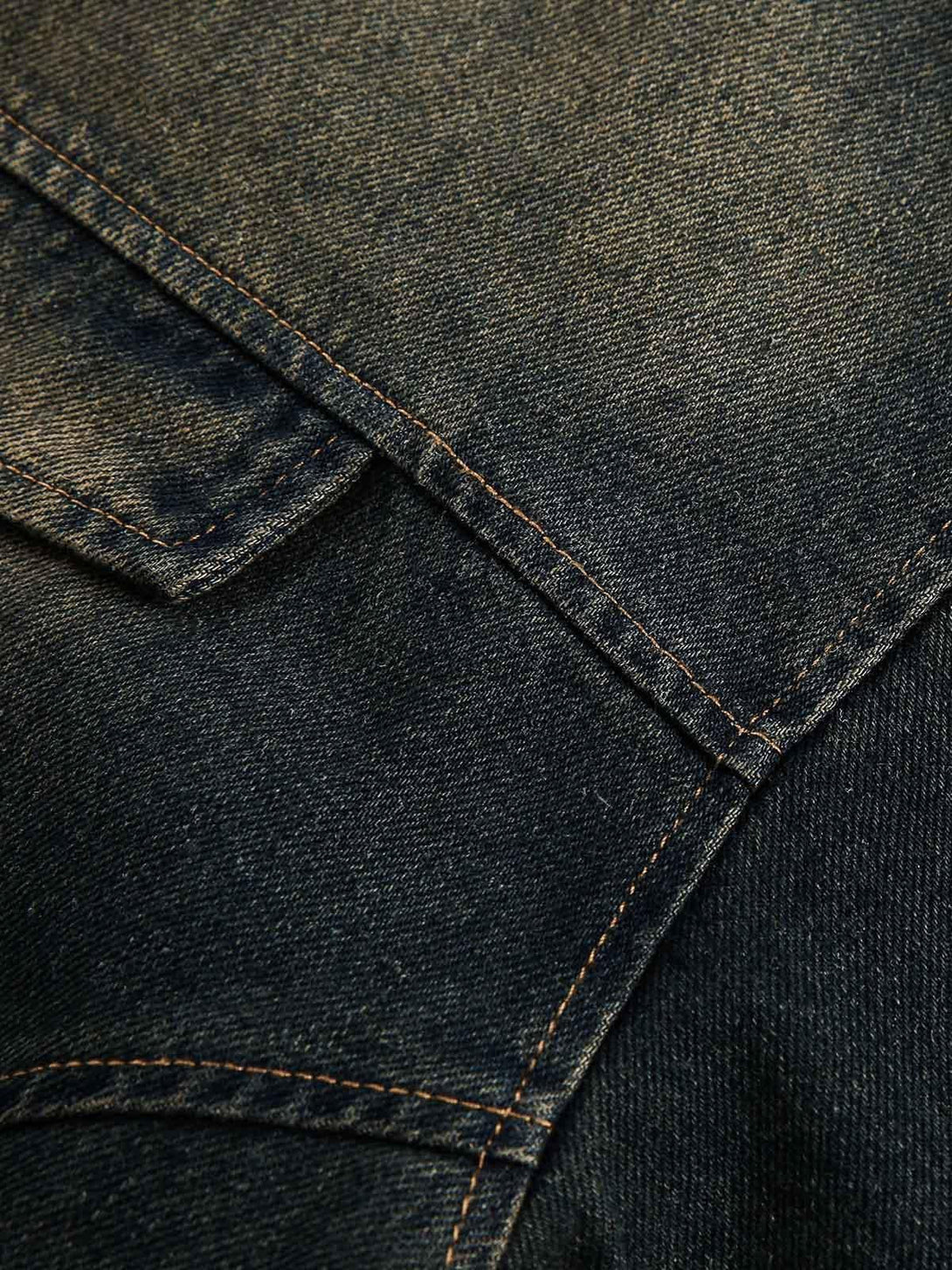 Detailed fabric and stitching of a TALISHKO washed distressed denim jacket, focusing on pocket design.