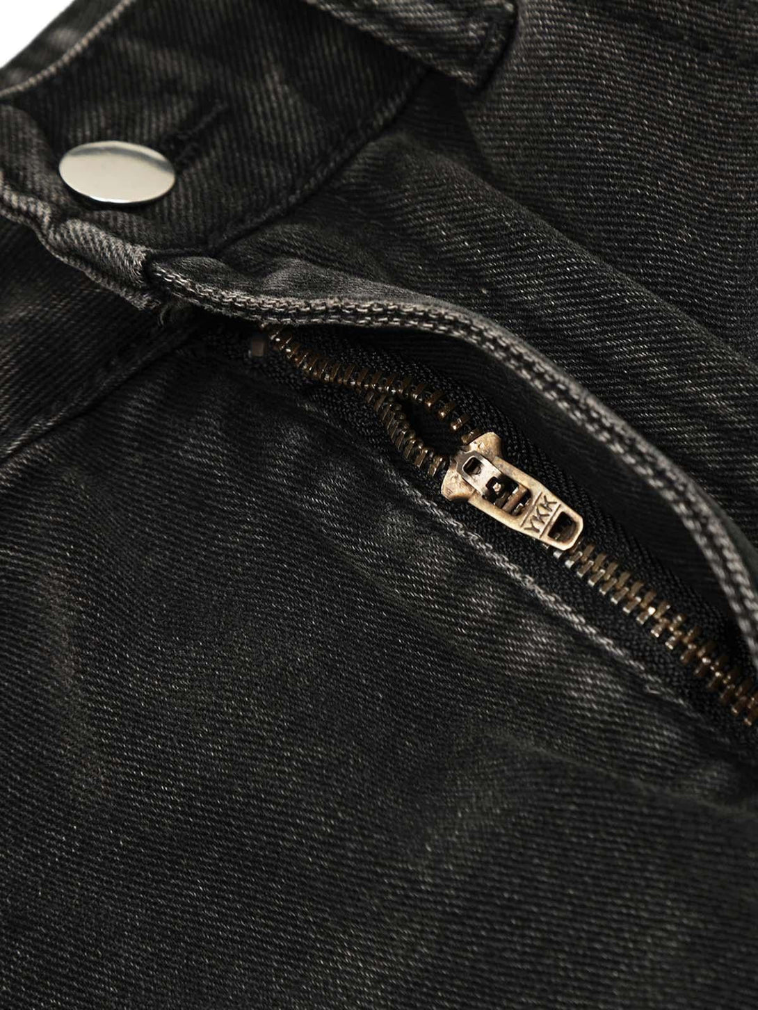 A detailed view of TALISHKO's washed cargo jeans, focusing on the zipper and fabric texture.
