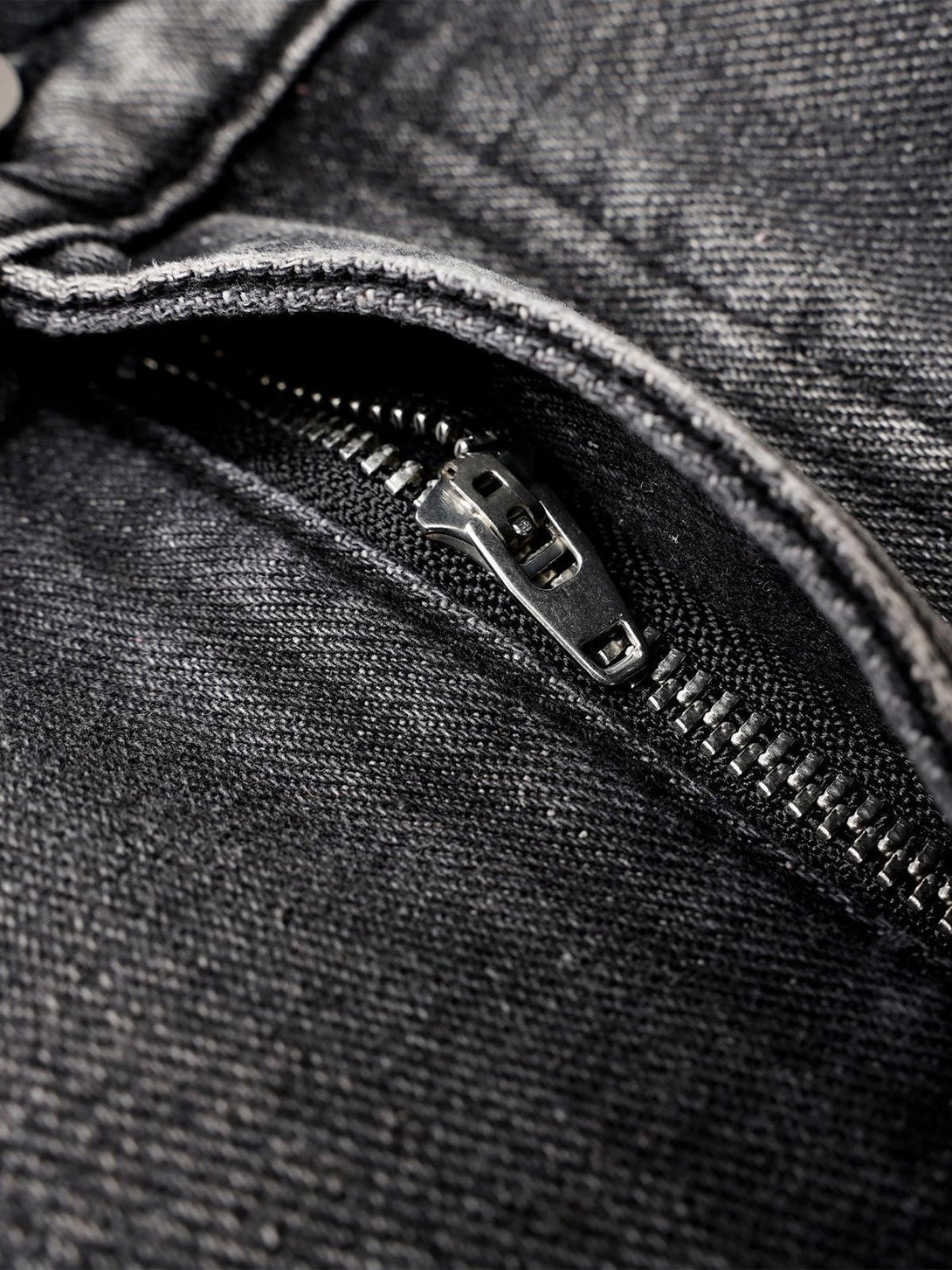 A tight crop highlighting the zipper detail on TALISHKO's washed distressed pleated cargo jeans.