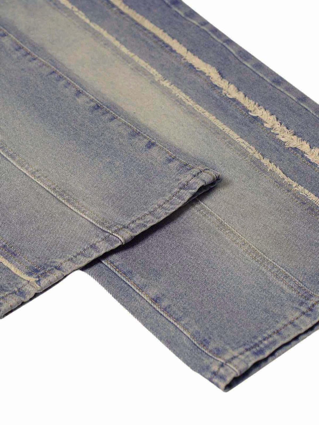 A detailed view of TALISHKO baggy jeans highlighting the washed, distressed raw edges.