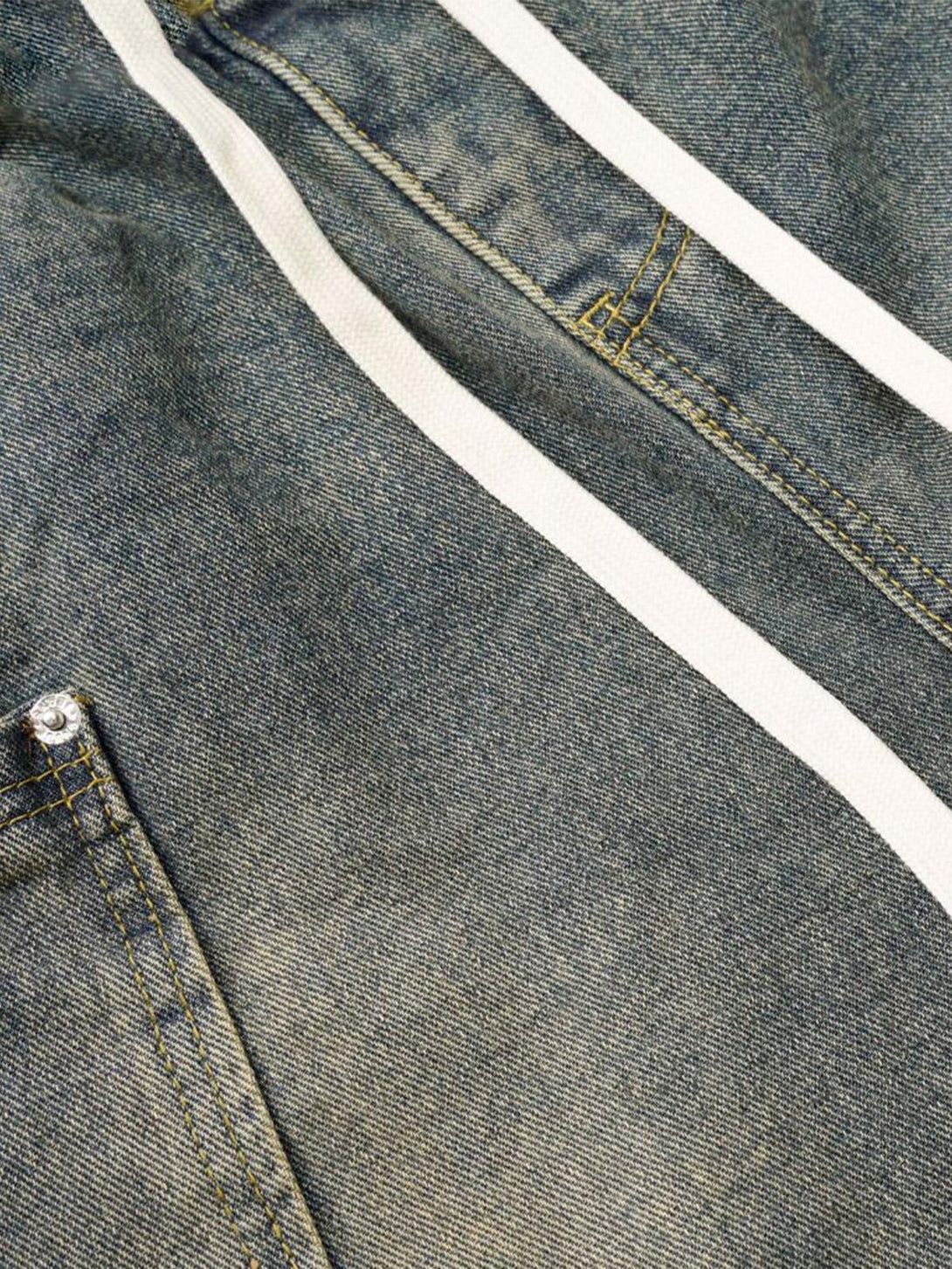 Detailed view of TALISHKO barrel jeans, showcasing distinctive stitching and distressed texture.