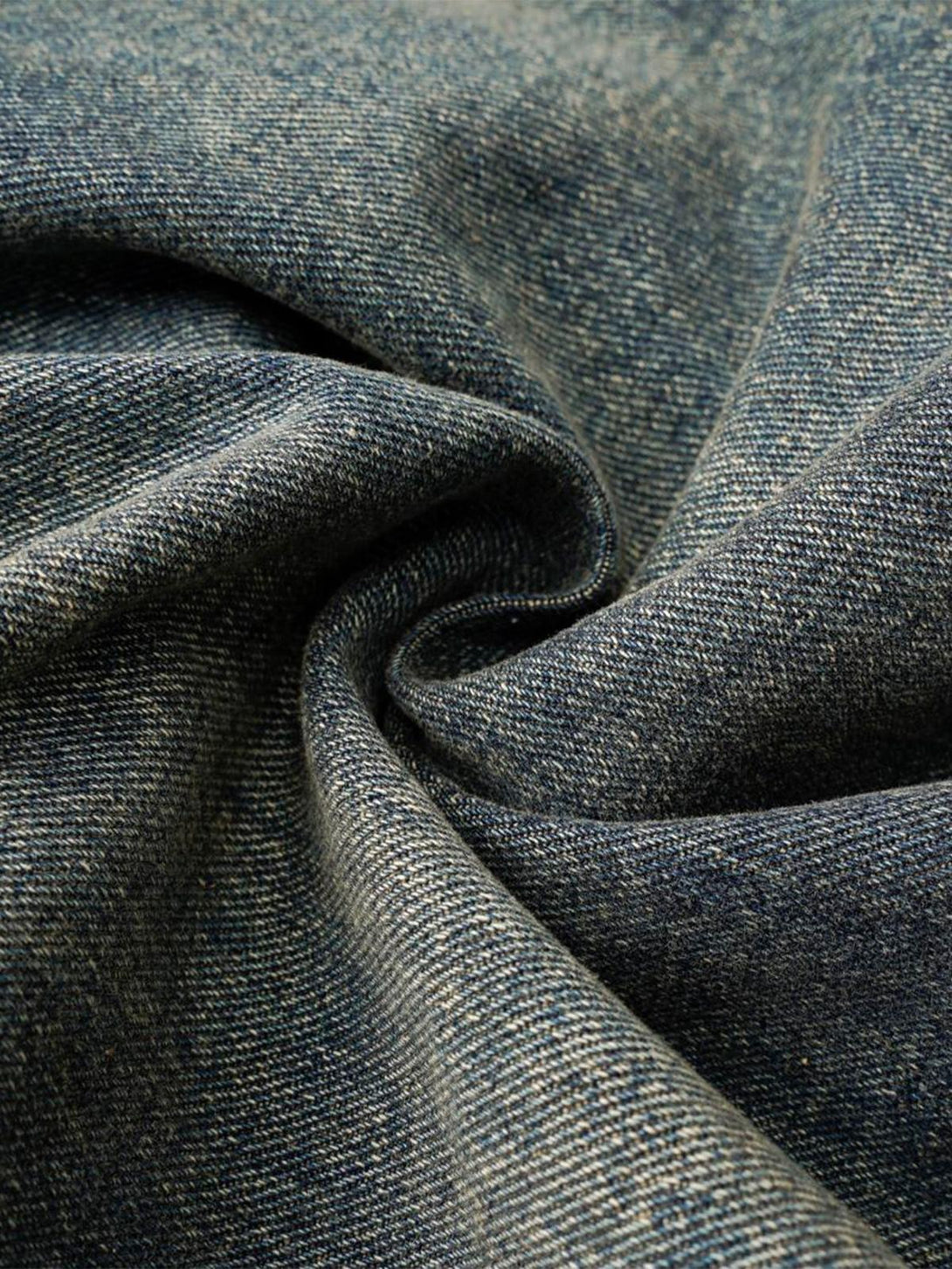 Zoomed-in texture of TALISHKO jeans, showcasing the washed distressed fabric and weave.