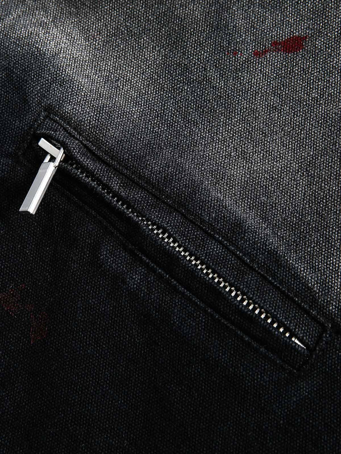 A detailed view of the TALISHKO denim jacket pocket, showcasing the sleek zipper and texture.