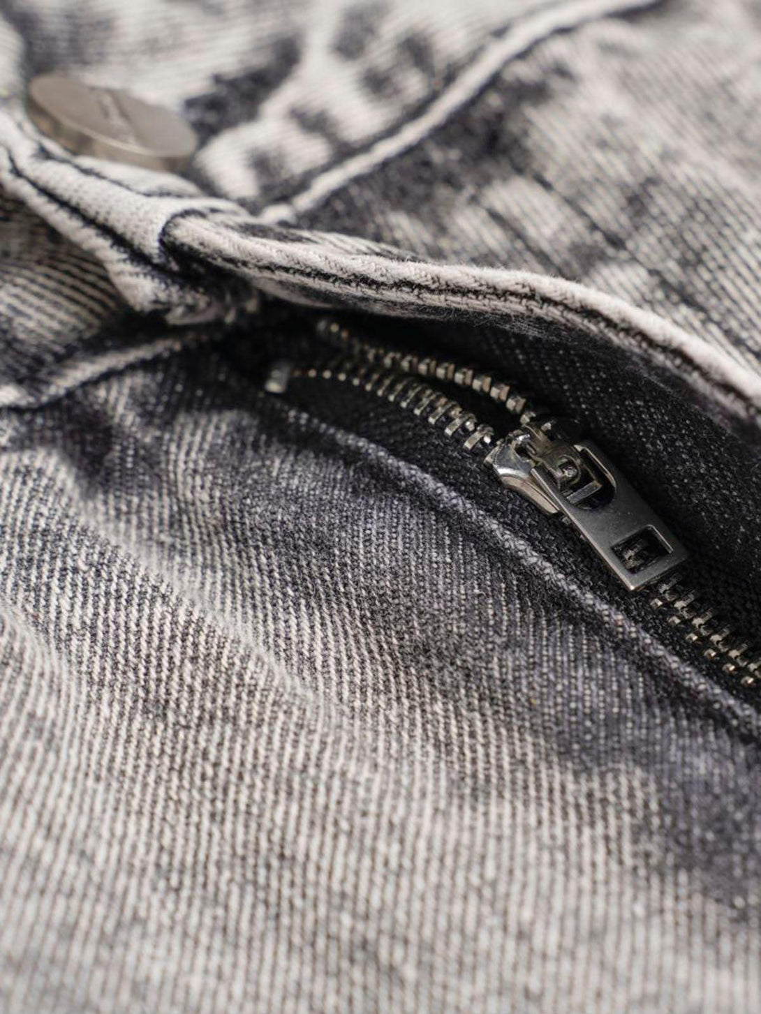 A tight crop highlighting the zipper detail on washed cargo jeans by TALISHKO.