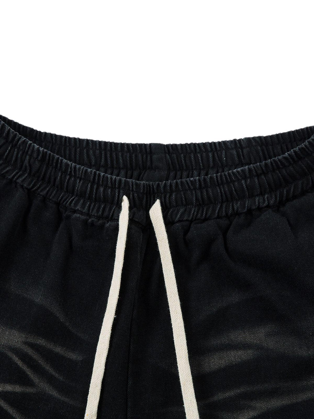 Focusing on the drawstring detail of TALISHKO's washed cargo jeans, highlighting the elastic waistband.