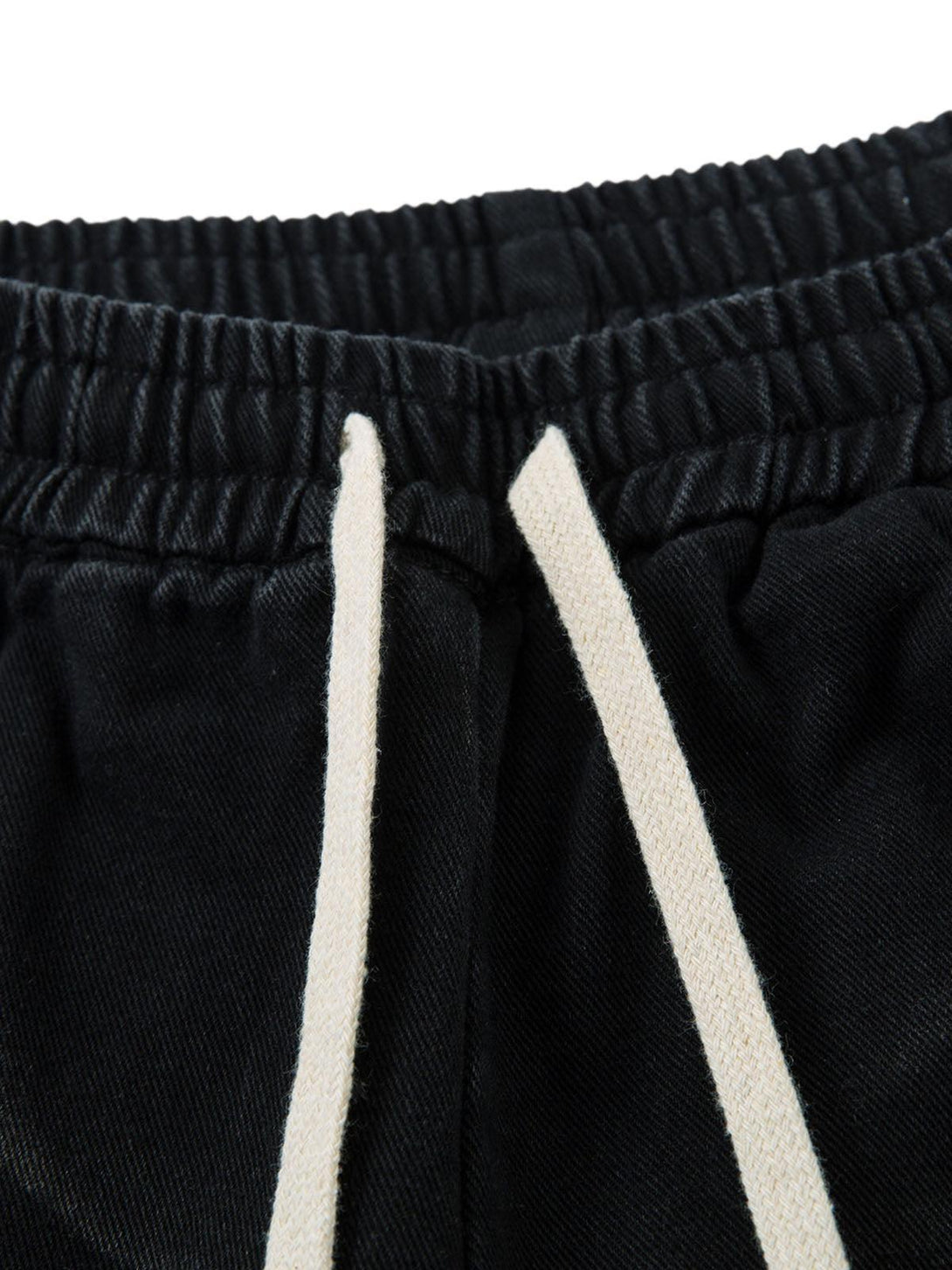 TALISHKO's washed cargo jeans feature a close-up of the elastic waistband and drawstring detail.