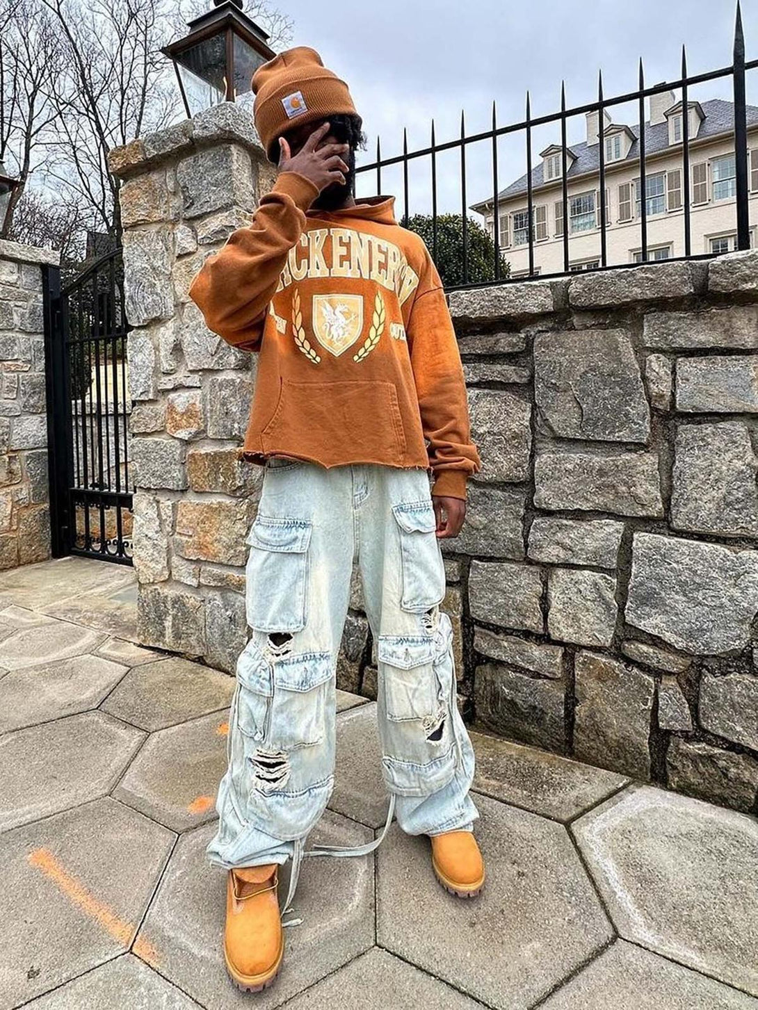 Model wearing TALISHKO washed cargo jeans with multiple pockets and a cozy brown hoodie.