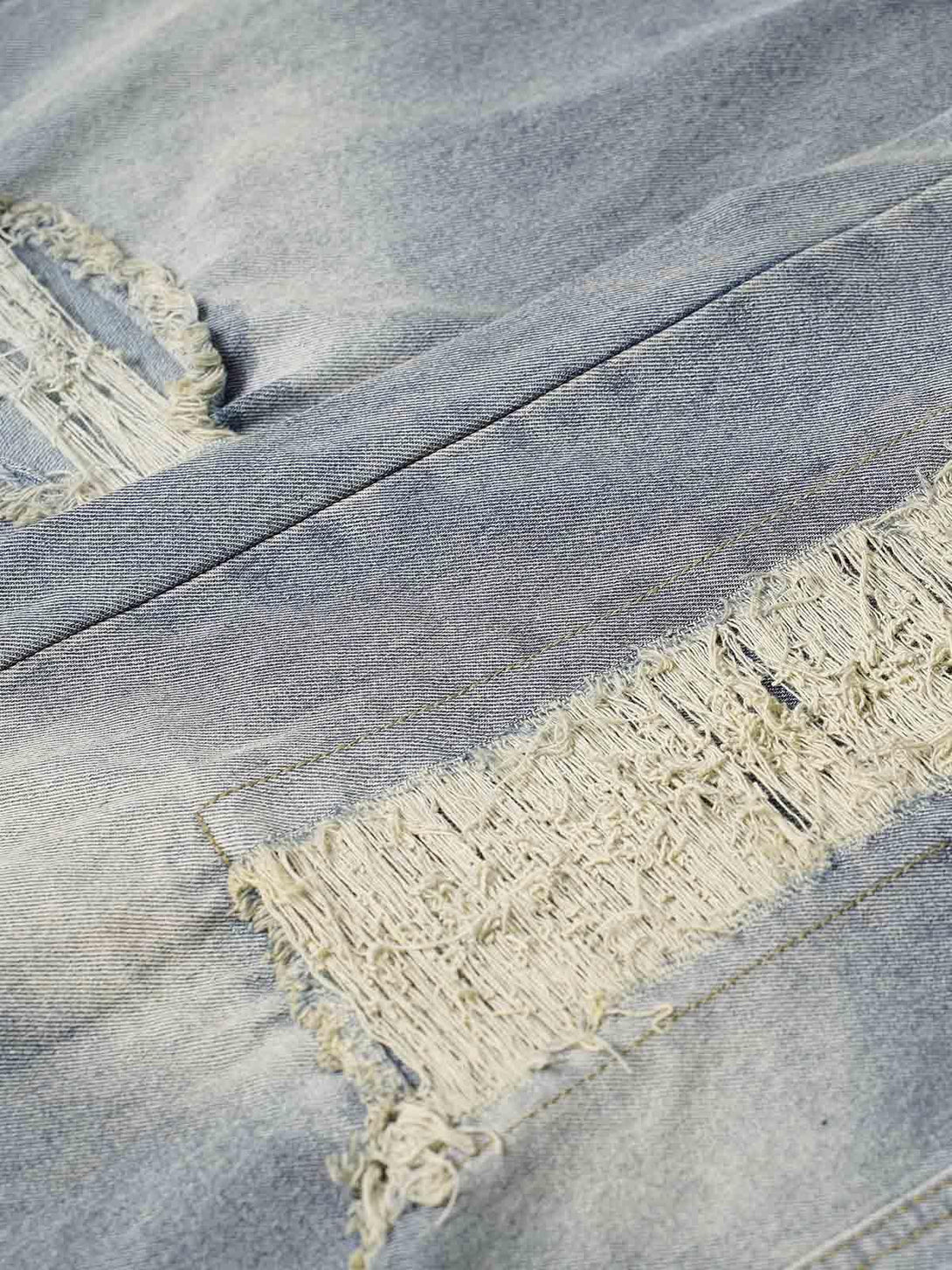 Zoomed-in texture of TALISHKO jeans, showcasing frayed detailing and a washed, ripped design.