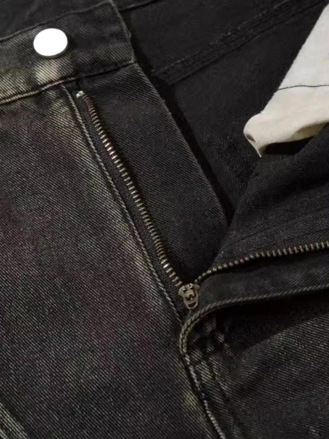 A detailed view of TALISHKO’s washed hip-hop horn jeans, highlighting the unique zipper design.
