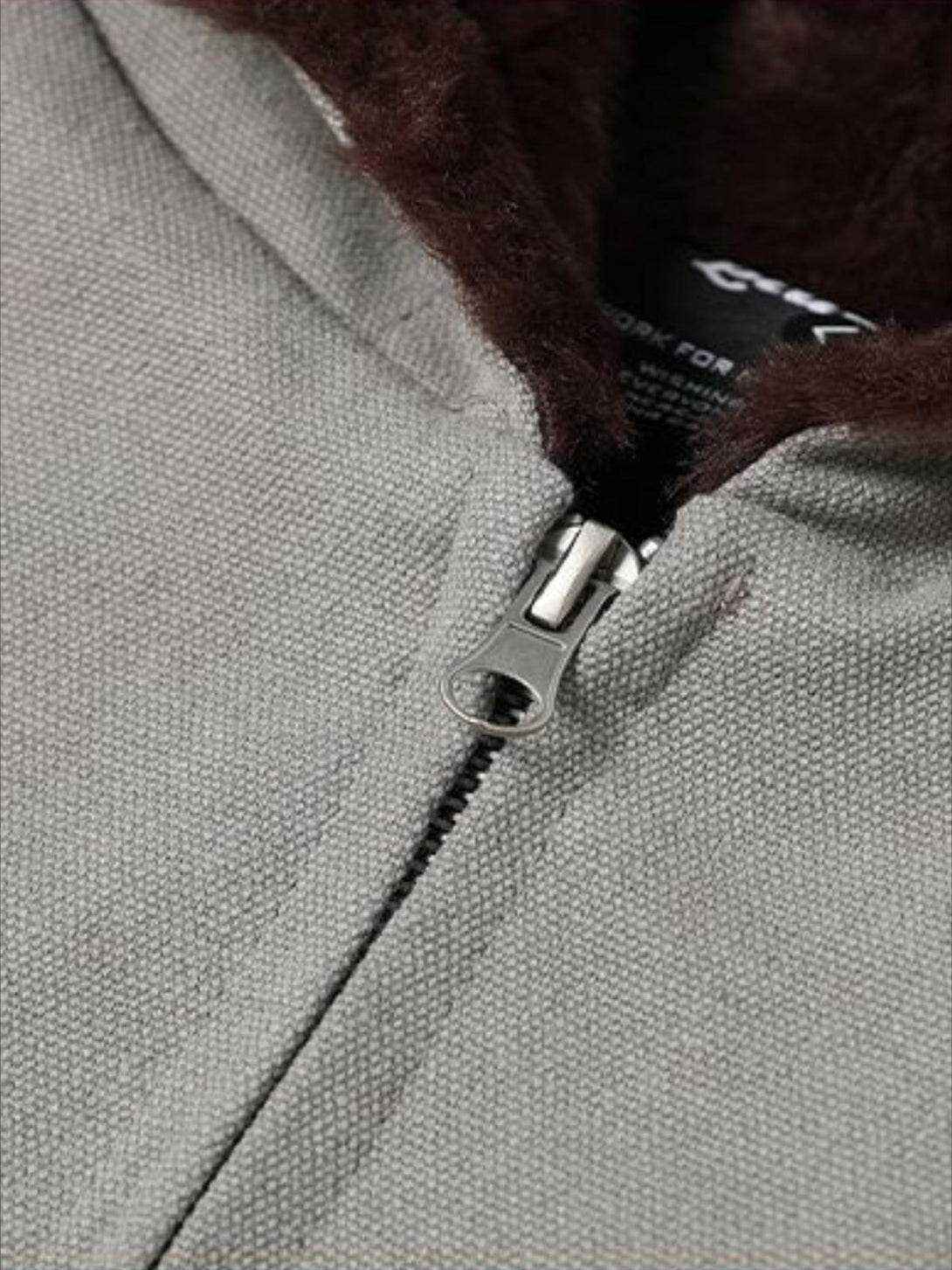 A detailed view of TALISHKO's washed zip-up hooded jacket, highlighting its textured fabric.
