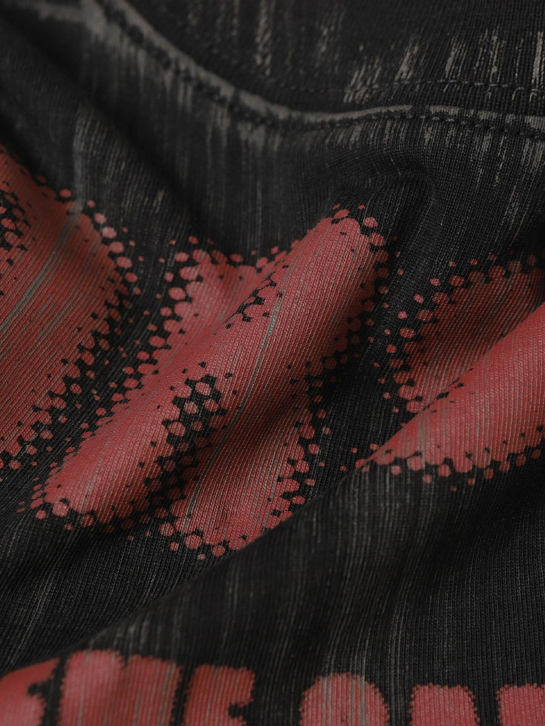 Focusing on the textured fabric of TALISHKO's graphic T-shirt, showcasing red and black dye patterns.