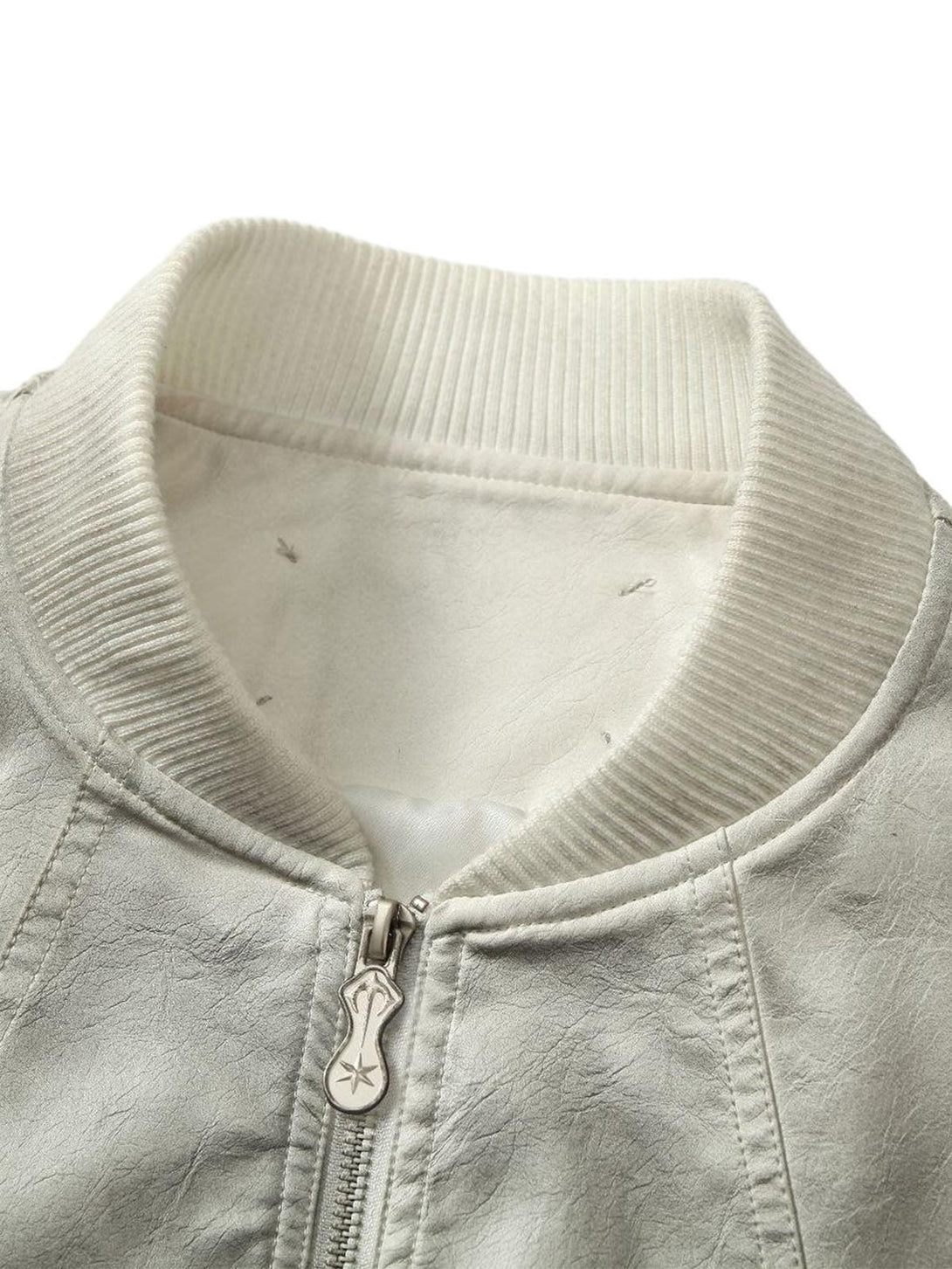 A detailed view of TALISHKO's leather bomber jacket collar, featuring ribbed texture and zip detail.