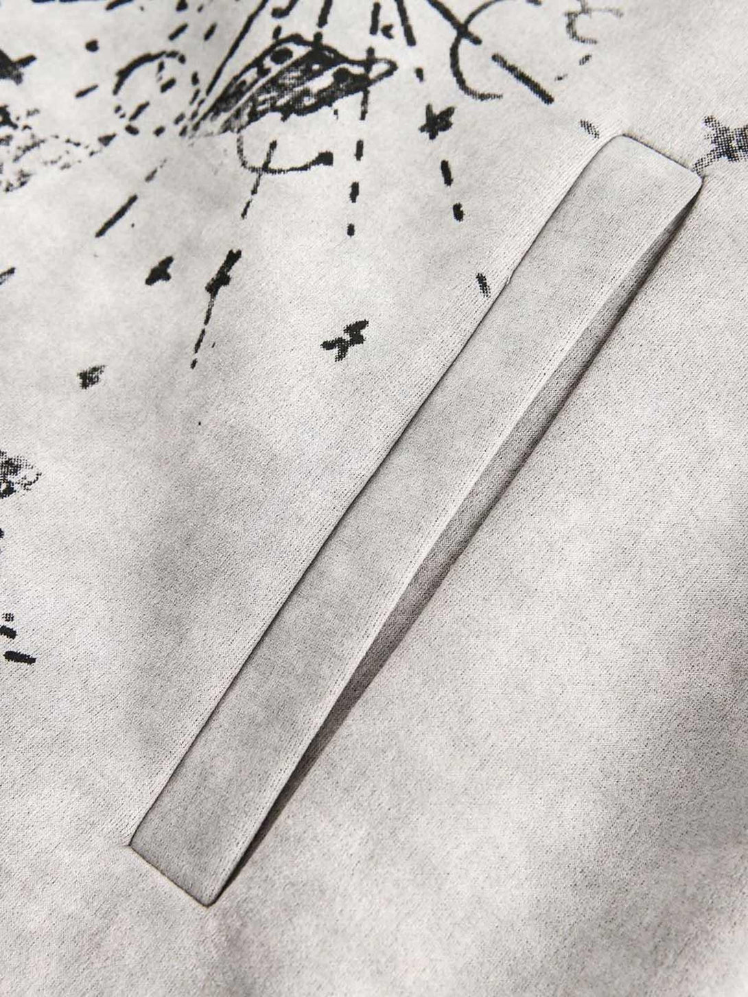 A tight crop highlighting the pocket detail of TALISHKO's patchwork graffiti zip-up jacket.