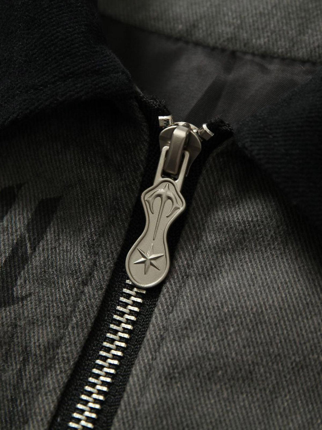 A detailed view of TALISHKO's barn jacket zipper, highlighting intricate metalwork and texture.