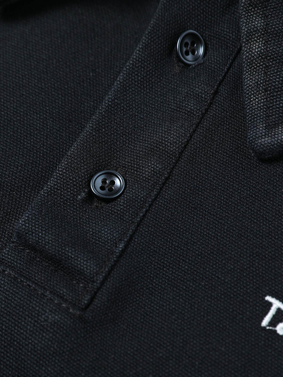 Intricate look at TALISHKO's black shirt collar with button details, showcasing texture.