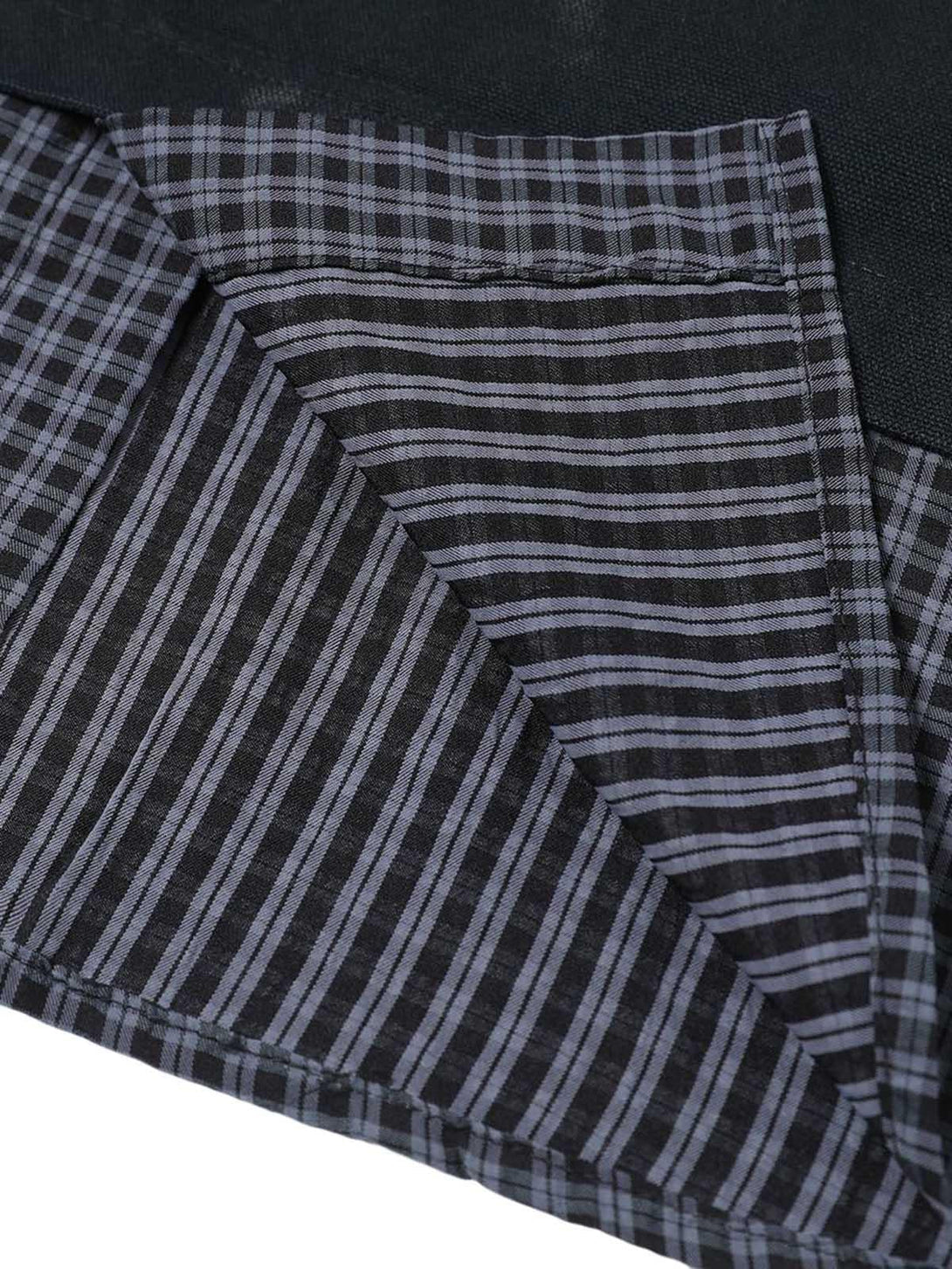 A close-up of TALISHKO's retro shirt hem with plaid patterns, showcasing intricate stitching.