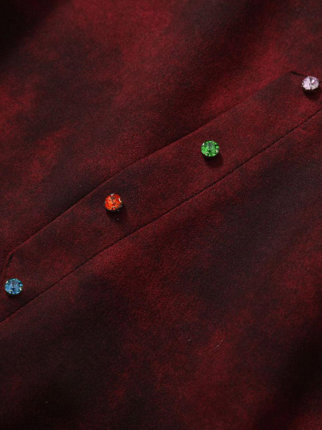 A close-up of TALISHKO's red tie-dye zipper jacket, highlighting colorful gemstone buttons.
