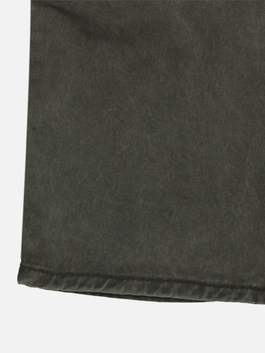 Zoomed-in texture of TALISHKO's baggy denim overalls, highlighting the hem detail.
