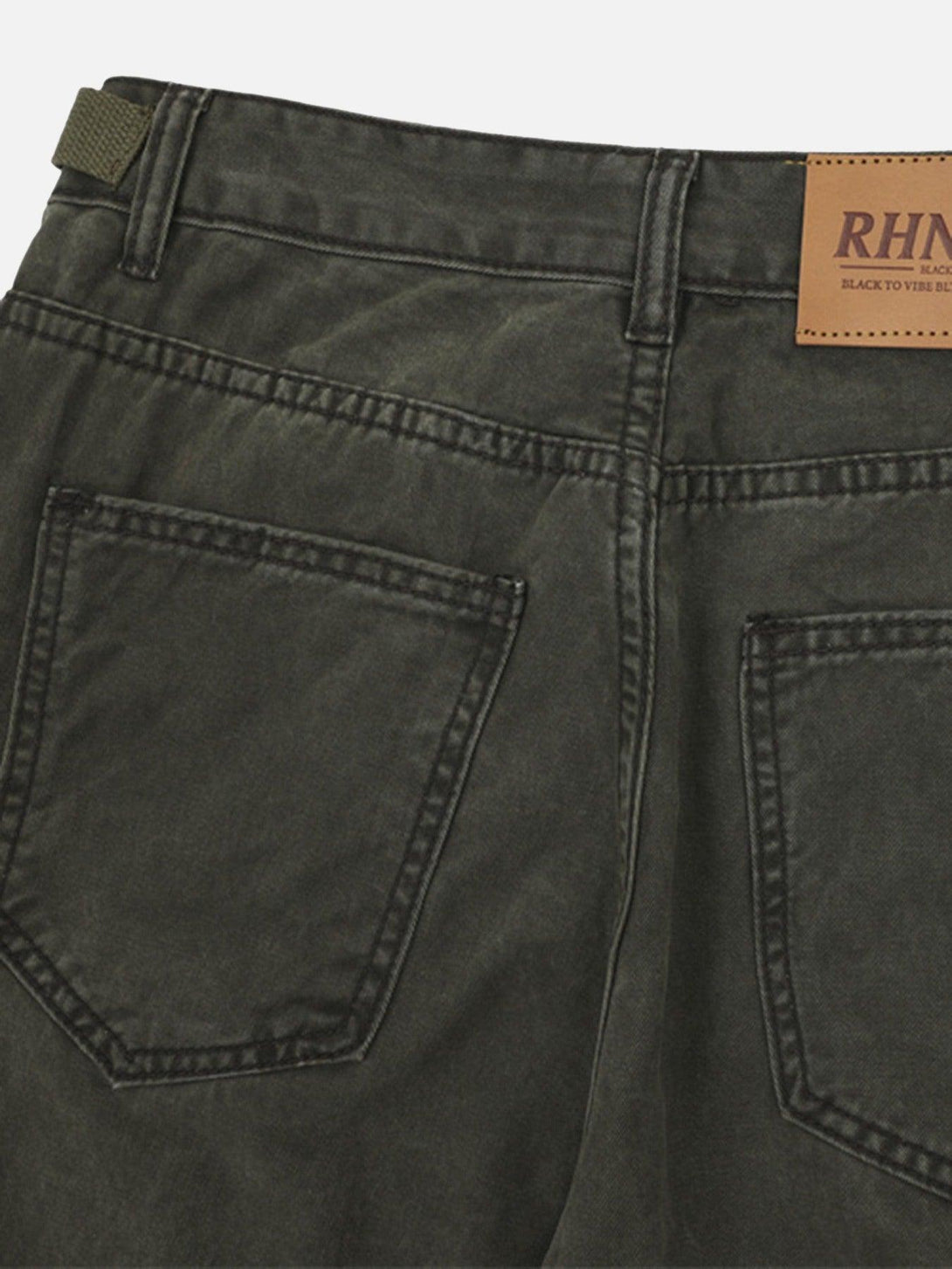 A close-up of TALISHKO's dark denim overalls, highlighting the back pockets and stitching.