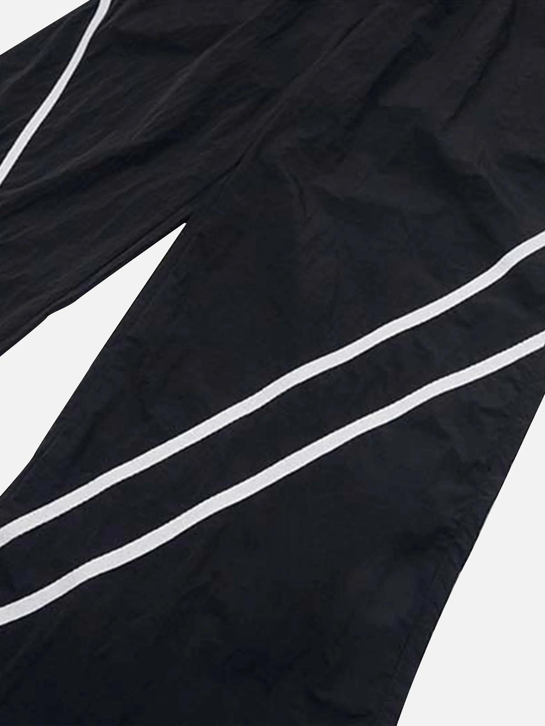 Close-up of TALISHKO black sweatpants with white stripes, highlighting sleek design details.