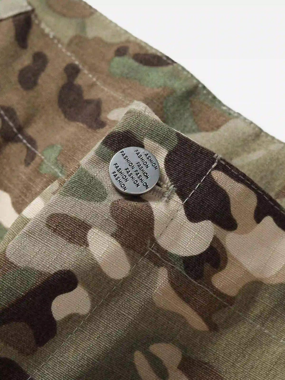 A close-up of TALISHKO camouflage pants, showcasing button detail and rugged workwear fabric.