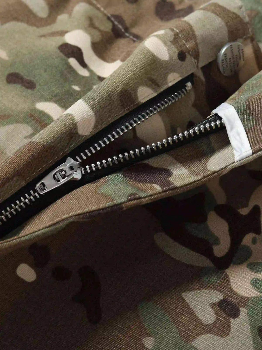 Focusing on the zipper detail of TALISHKO camouflage pants, highlighting durable street style.